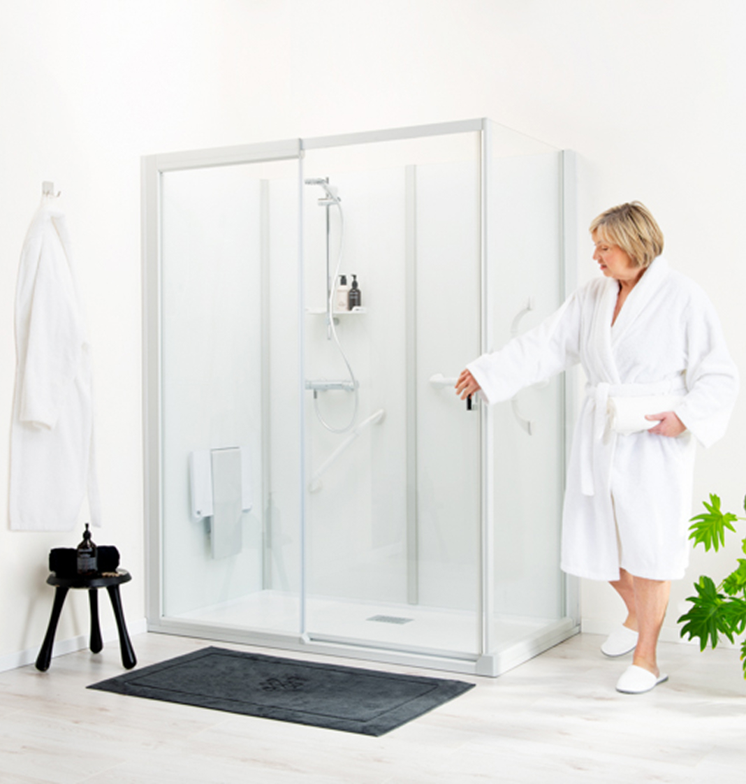 Vrouw met badjas staat in badkamer met haar hand op een deur van de douche